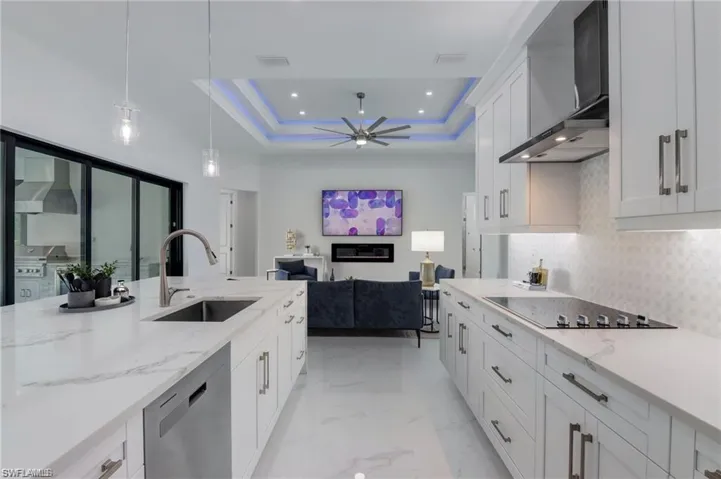 Kitchen featuring white cabinets, wall chimney exhaust hood, a raised ceiling, and black electric cooktop
