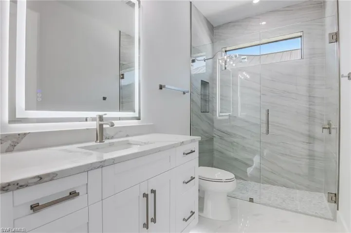 Bathroom featuring vanity, toilet, and a shower with door