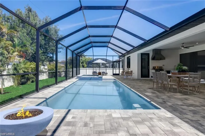 View of swimming pool with glass enclosure, ceiling fan, a patio area, and a grill