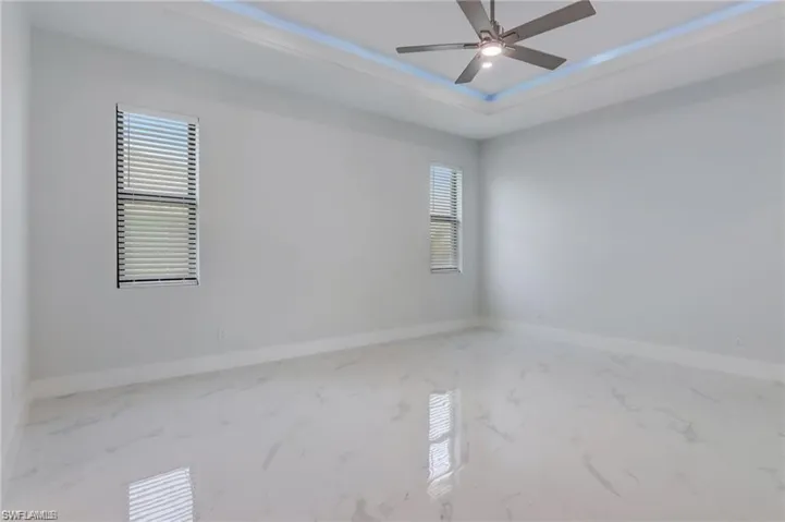 Unfurnished room with a tray ceiling and ceiling fan