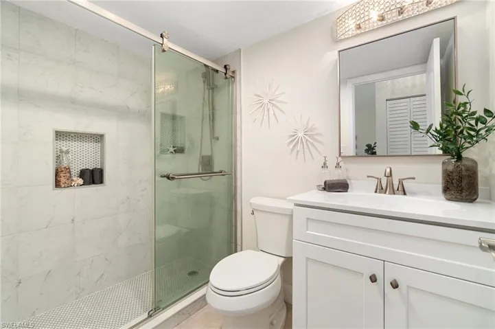White marble and decorative tiles accent the walk-in shower.  White quartz counter top and new modern white vanity, a fixtures.