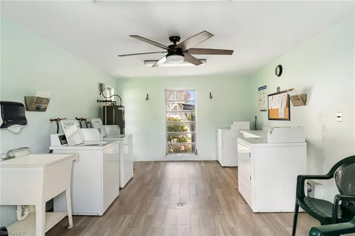 Shared laundry room featuring washing machine and dryer, a ceiling fan, light wood finished floors, and water heater