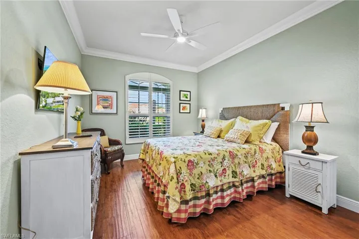 Bedroom with crown molding, wood finished floors, a textured wall, and a ceiling fan