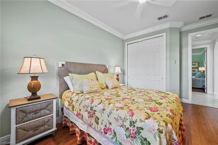 Bedroom with dark wood finished floors, ornamental molding, a closet, and a ceiling fan