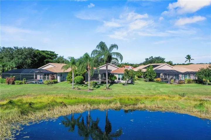 Rear view of house featuring a water view, a sunroom, a lawn, and glass enclosure