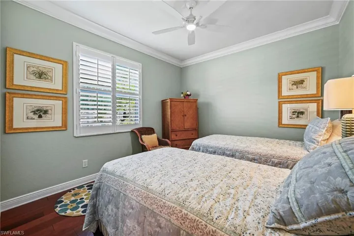 Bedroom featuring ornamental molding, dark wood-style flooring, and a ceiling fan