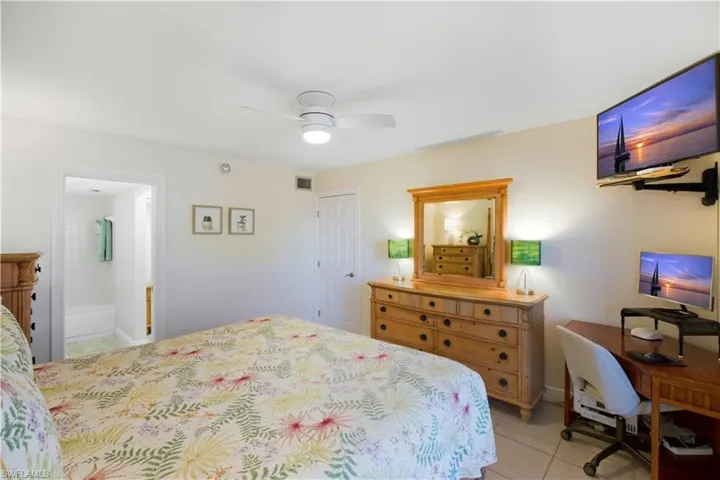 Bedroom with light tile patterned floors, an office area, and a ceiling fan