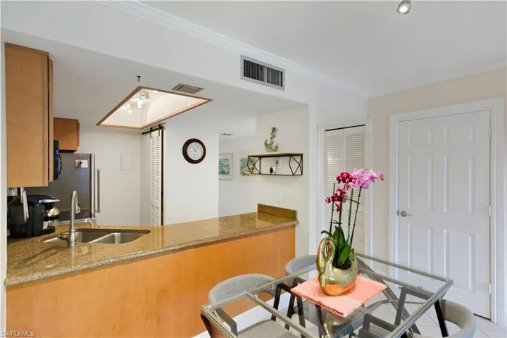 Kitchen featuring brown cabinets, light stone counters, a peninsula, ornamental molding, and open shelves