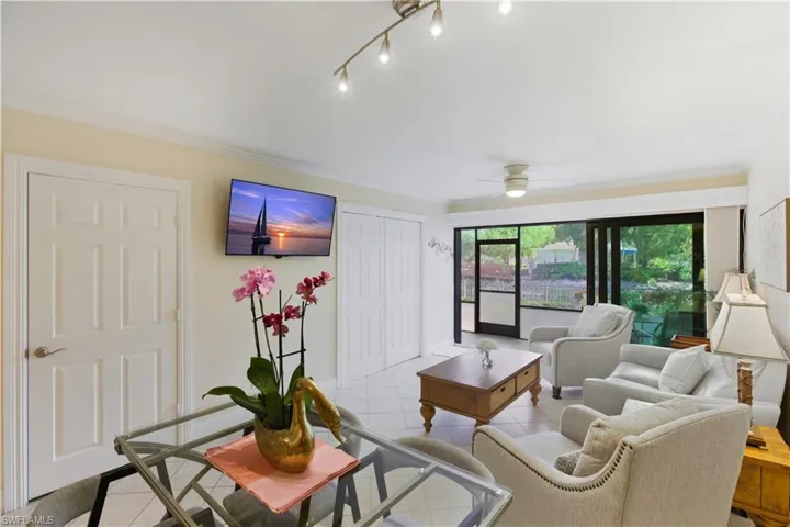 Living area with tile patterned flooring, crown molding, and a ceiling fan
