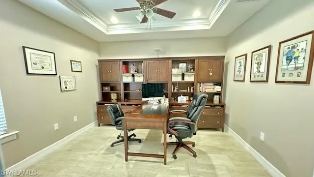 Office area featuring ceiling fan, ornamental molding, light tile patterned floors, and a tray ceiling