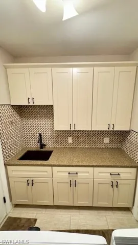 Laundry Room with off white cabinets, custom backsplash, sink and pantry.