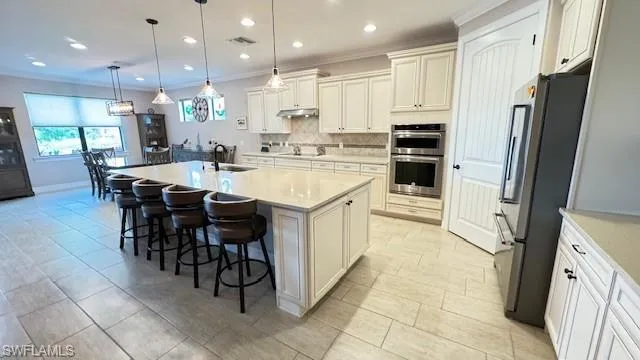 Kitchen with sink, stainless steel appliances, a kitchen breakfast bar, pendant lighting, and a center island with sink