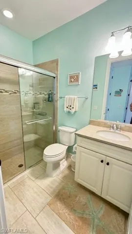Bathroom with tile patterned flooring, vanity, toilet, and a shower with shower door