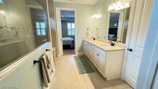 Bathroom with tiled shower, vanity, and an inviting chandelier