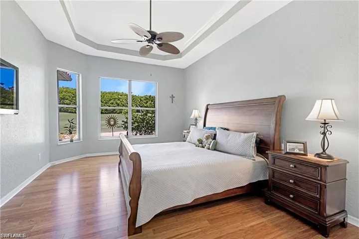 Bedroom with a textured wall, light wood-type flooring, and ceiling fan