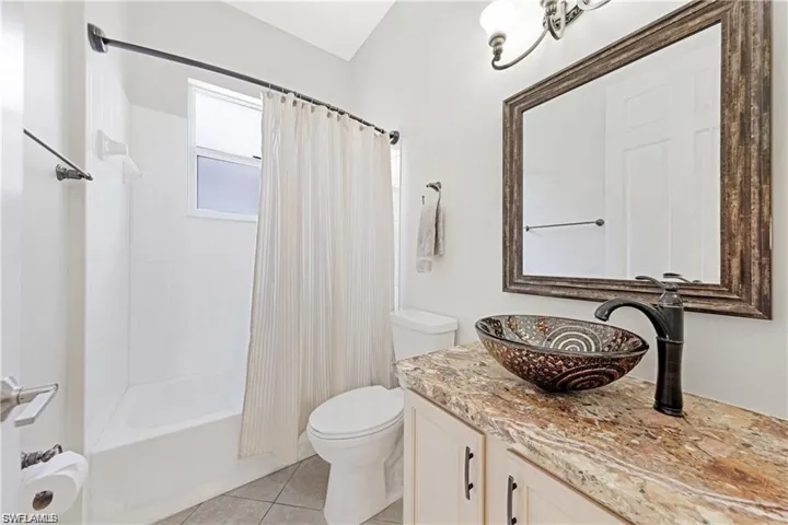 Full bath featuring vanity, shower / bath combo with shower curtain, and light tile patterned floors