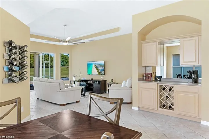 Dining area with a raised ceiling, light tile patterned floors, and a ceiling fan