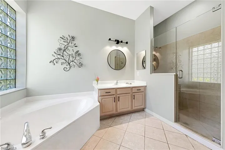 Bathroom featuring vanity, light tile patterned floors, a shower stall, and a bath