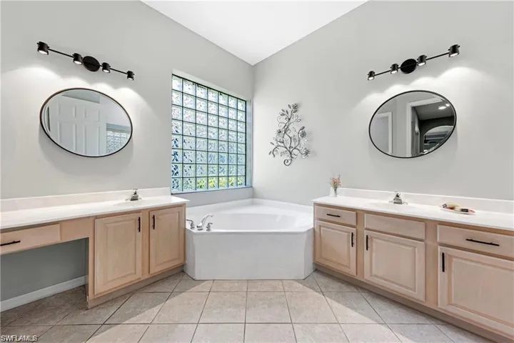 Full bathroom with two vanities, a garden tub, and light tile patterned flooring