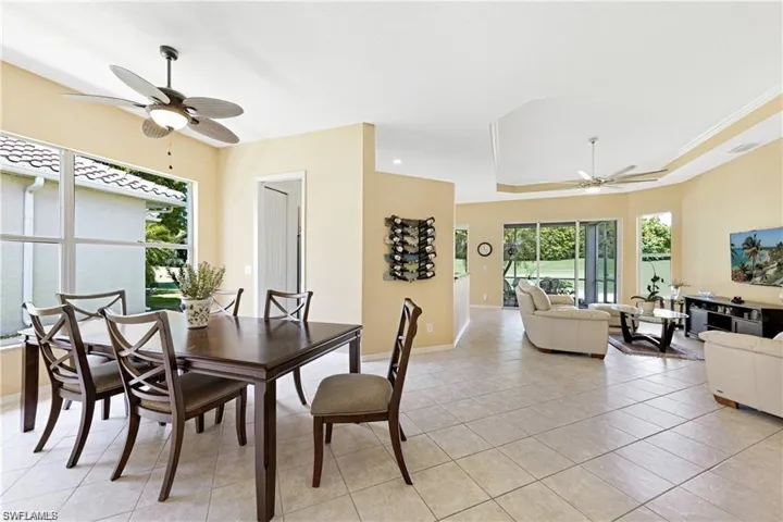 Dining space featuring a ceiling fan, a raised ceiling, and light tile patterned flooring