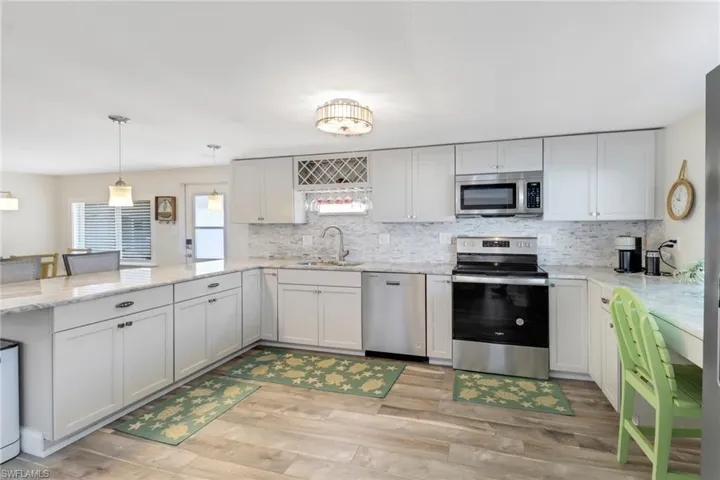 Kitchen with light hardwood / wood-style floors, backsplash, appliances with stainless steel finishes, sink, and pendant lighting