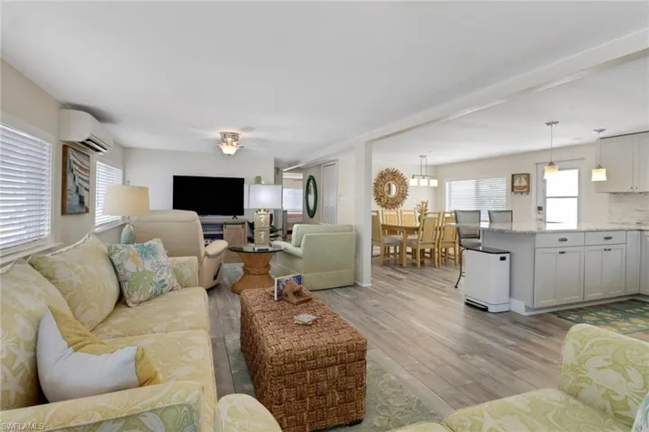 Living room featuring ceiling fan with notable chandelier, light hardwood / wood-style floors, and a wall mounted air conditioner