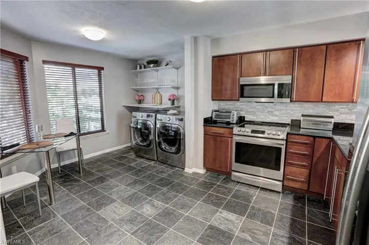 Kitchen featuring  stainless steel appliances, washing machine and dryer, and backsplash