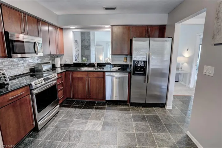 Kitchen with decorative backsplash, stainless steel appliances, and sink