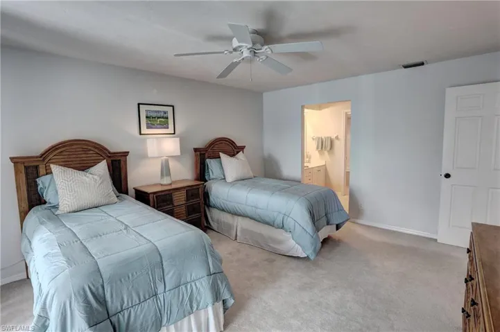 Bedroom with ensuite bath, light carpet, and ceiling fan