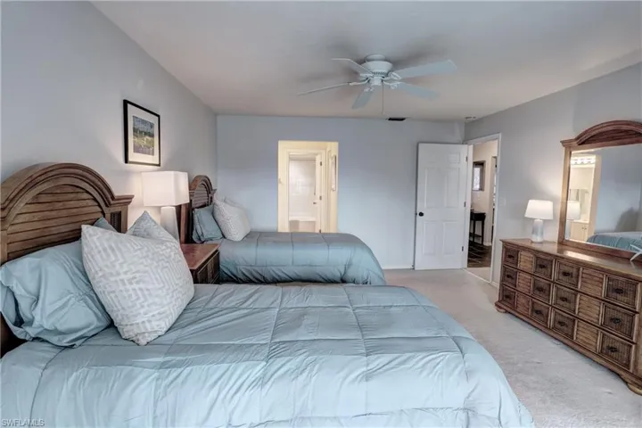 Carpeted bedroom featuring ceiling fan and ensuite bathroom