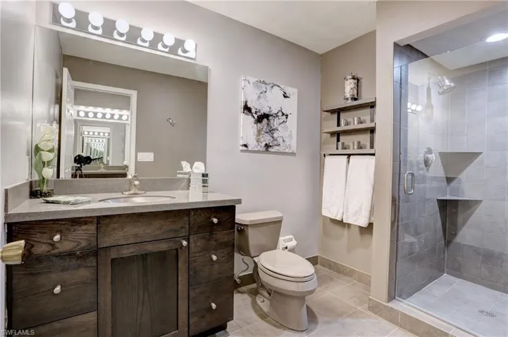 Bathroom with vanity, an enclosed shower, toilet, and tile patterned flooring
