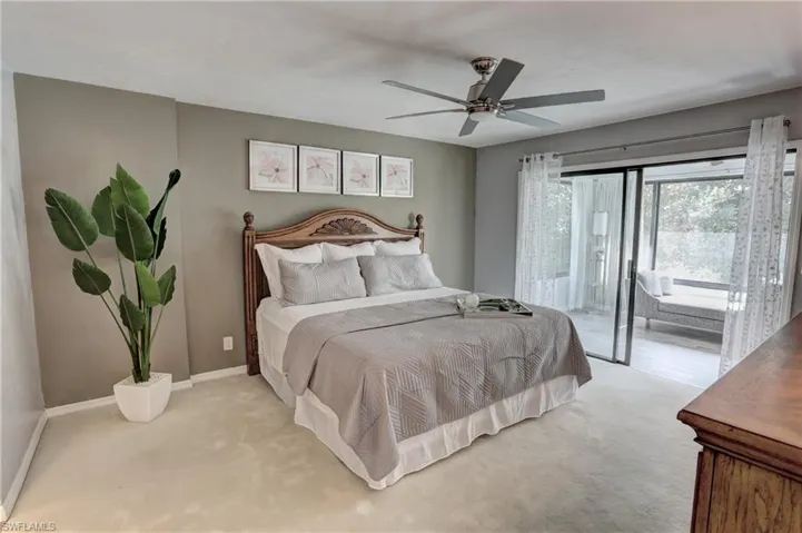 Carpeted bedroom featuring access to exterior sunroom and ceiling fan
