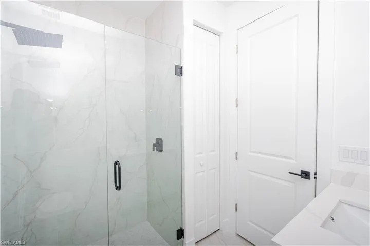 Bathroom with a marble finish shower, vanity, and a closet