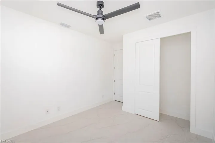 Unfurnished bedroom featuring light marble finish flooring and ceiling fan
