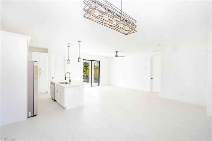 Kitchen with white cabinetry, decorative light fixtures, a center island with sink, and open floor plan