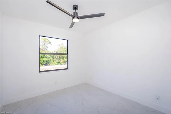 Spare room with marble look tiles and a ceiling fan