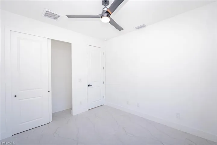 Unfurnished bedroom featuring a closet, ceiling fan, and light marble finish flooring