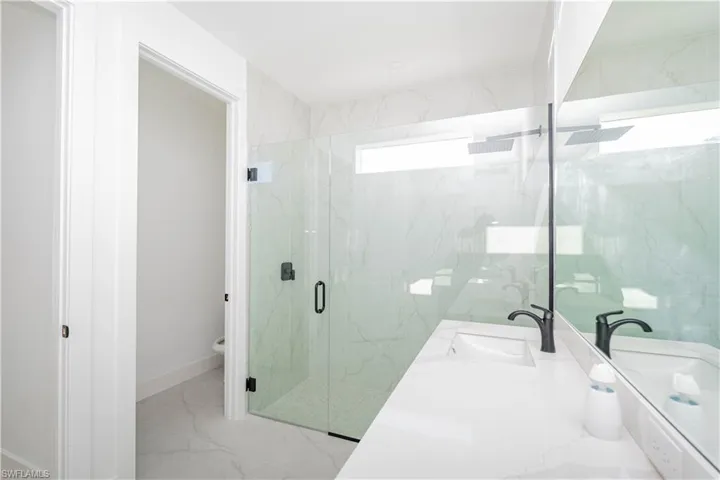 Bathroom with a marble finish shower, light marble finish flooring, and vanity