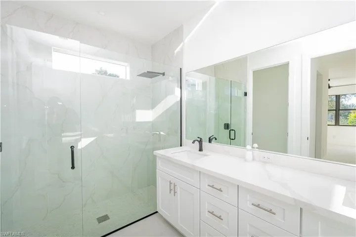 Bathroom with double vanity and a marble finish shower