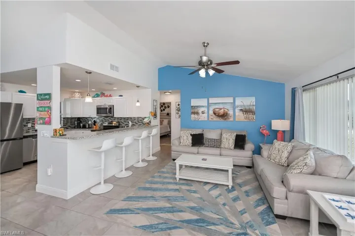 Living area featuring vaulted ceiling, a ceiling fan, and light tile patterned floors