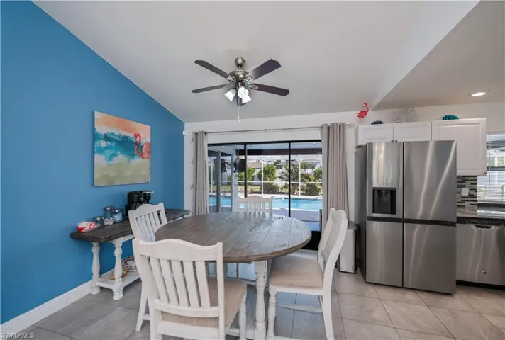 Dining room with light tile patterned floors, vaulted ceiling, plenty of natural light, a sunroom, and ceiling fan