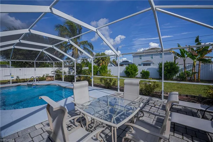 View of pool with a fenced backyard, glass enclosure, a patio, a sunroom, and outdoor dining area