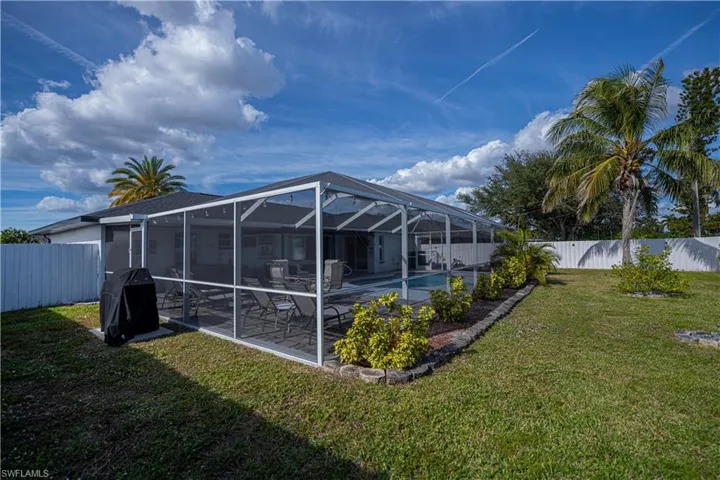 Rear view of house featuring a fenced backyard, glass enclosure, and a sunroom