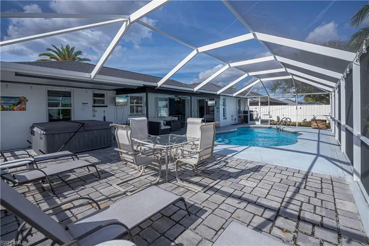 Outdoor pool with a sunroom, enclosure, a patio, a hot tub, and outdoor dining space