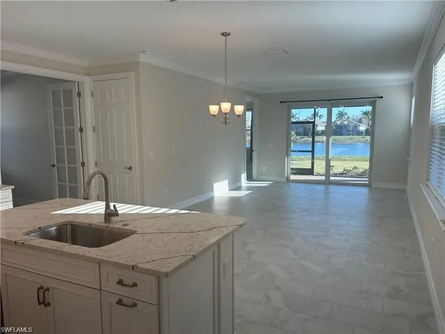 Kitchen featuring white cabinetry, light stone countertops, open floor plan, ornamental molding, and a water view
