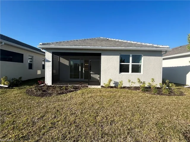Rear view of house with a sunroom, stucco siding, and a yard