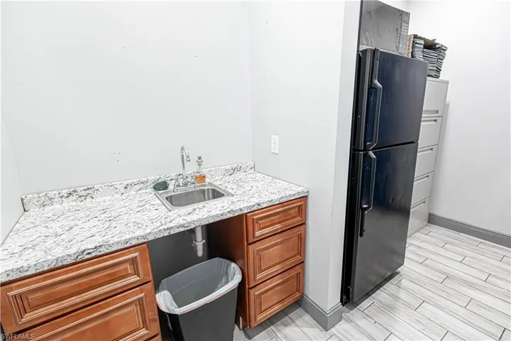 Built-in cabinetry with wood-finish doors, granite-style countertop, stainless steel sink with chrome faucet, and tiled flooring
