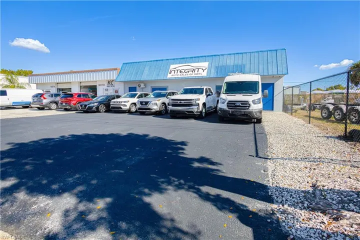 Commercial building with a blue metal roof, white exterior walls, and an asphalt parking lot