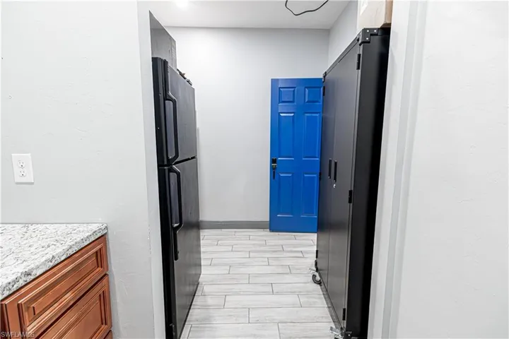 Wood-finish flooring, light gray wall paint, and a bright blue door
