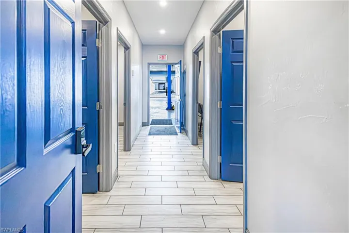 Hallway featuring wood-finish flooring, recessed lighting, and blue paneled doors